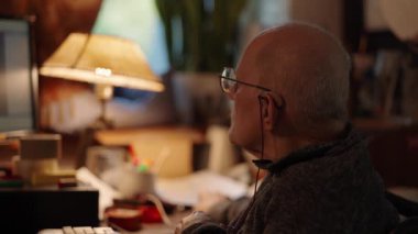 Kronik engelli yaşlı yetişkin tekerlekli sandalyede oturan bilgisayarla çalışıyor.