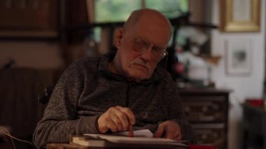 Kronik engelli yaşlı yetişkin tekerlekli sandalyede oturan masaüstü bilgisayarının evraklarıyla çalışıyor.