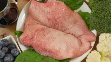Mutfak masasındaki diğer malzemelerin yanında çiğ ördek göğsü filetosu sunuluyor.