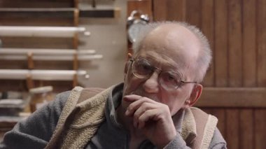 Tekerlekli sandalyedeki kıdemli yaşlı kuyumcu bir atölyede çalışıyor.