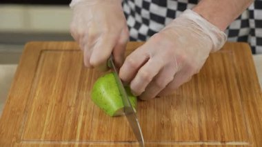 Şef tahtada taze armut kesip biçiyor.