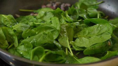 Kızartma tavasında taze ıspanak ve karamelli soğan.