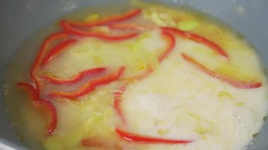 Şef tavada Tom Yum çorbası pişirirken sebzeleri karıştırıyor.