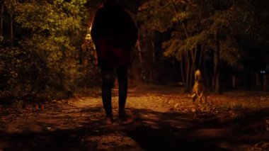 Genç bir kadın banliyö bölgesinde köpeğini gezdiriyor.