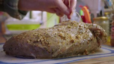 Ev hanımı kızartılması için marine edilmiş çiğ dana etini bağlıyor.