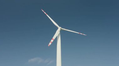 Güneşli bir günde mavi gökyüzüne karşı dönen rüzgar türbini