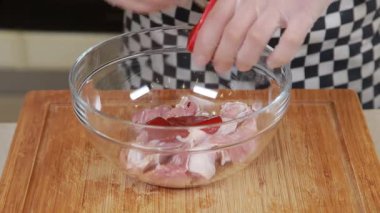 Şef cam kasede taze tavuk bacağı pişiriyor.