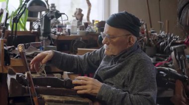 Tekerlekli sandalyedeki yaşlı erkek usta atölyesinde mobilyaları restore ediyor.