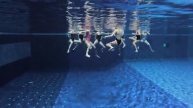 Senkronize yüzme takımı yüzme havuzunda, su altında antrenman yapıyor.