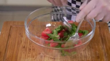 Şef cam kasede taze sebze salatası hazırlıyor.