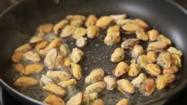 Şef tavada deniz ürünleri kokteyli pişiriyor.