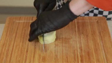 Bir şef patlıcanları tahta bir tahtanın üzerinde bıçakla doğruyor.