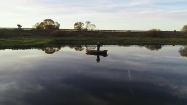 Gün batımında teknede bir balıkçının hava görüntüsü.