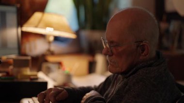 Kronik engelli yaşlı yetişkin tekerlekli sandalyede oturan bilgisayarla çalışıyor.