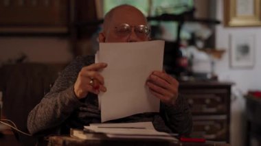 Kronik engelli yaşlı yetişkin tekerlekli sandalyede oturan masaüstü bilgisayarının evraklarıyla çalışıyor.