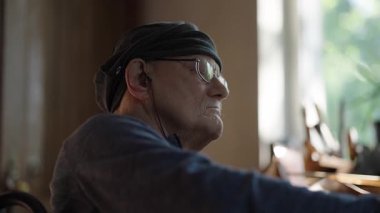 Tekerlekli sandalyedeki kıdemli sanatçı tuvaldeki yağlı boyaya altın sürüyor.