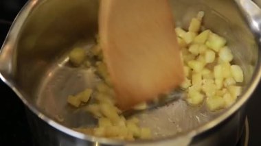 Şef, pide sandviçi doldurmak için tencereye tarçınlı elma karıştırıyor.