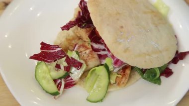 Kızarmış tavuk ve elma soslu Pita sandviçi taze salatayla servis edilir.