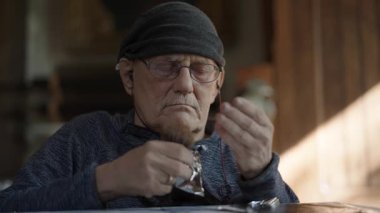 Tekerlekli sandalyedeki kıdemli sanatçı tuvaldeki yağlı boya resme gümüşü uygular.