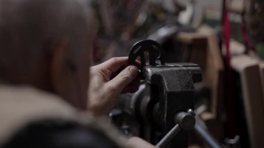 Evdeki atölyesinde tekerlekli sandalyede çalışan yaşlı bir zanaatkar.