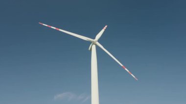 Güneşli bir günde mavi gökyüzüne karşı dönen rüzgar türbini