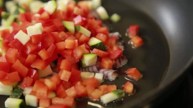 Şef sebze omleti pişirirken tavada doğranmış sebze kızartıyor.