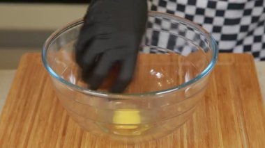 Şef omlet pişirirken cam bir kasede yumurta çırpıyor.