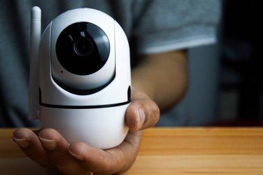 Beyaz ip kamera ahşap zeminde, adam ip kamera kullanıyor.