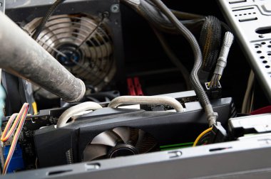 Photograph of a technician blowing dust from a computer