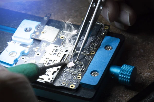 Top view, mechanic doing repairs Smartphone motherboard, smartphone repair, circuit repair