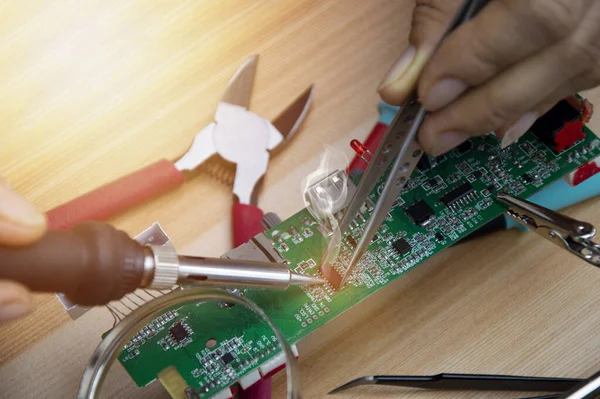 Teknisyen ana kartları ve lehimleme ekipmanlarını tamir ediyor, devreleri onarıyor..