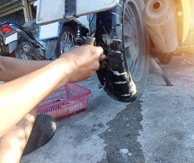 Motosiklet tamircisi lastikte bir delik açıyor..