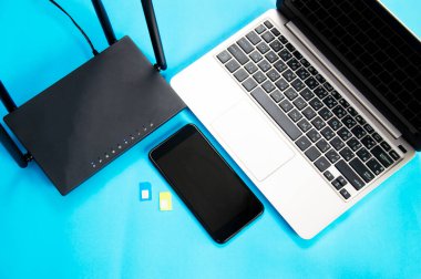 Wi-Fi yönlendirici, SIM kart, akıllı telefon, mavi arka planda dizüstü bilgisayar. İletişim ekipmanları