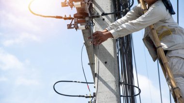 Teknisyen elektrik direğindeki kabloları tamir ediyor..