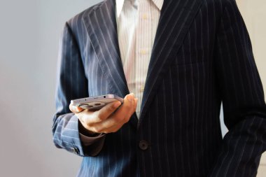 Adamın el ele tutuşması ve akıllı telefonu kullanırken, çalışırken, çalışırken, internette sörf yaparken, sosyal medyayı kontrol ederken ve mobil uygulamalar kullanırken. Modern iletişim kavramı.