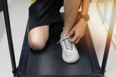 Asyalı bir adam koşu bandında koşmaya hazırlanıyor.