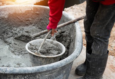 İşçiler inşaat alanında çimento karıştırıyorlar..