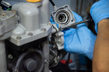 Bir teknisyen eski, bozuk bir otomatik su pompasını tamir ediyor..