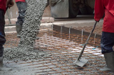 İşçiler inşaat alanına beton ve çimento döküyorlar.
