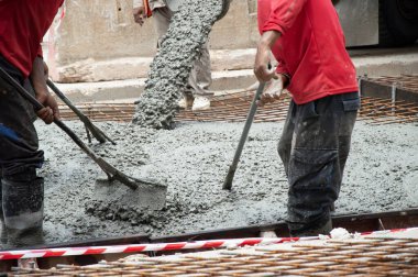 İnşaat işçisi beton döküyor. Beton dökme ve temel çalışmalarının yer aldığı