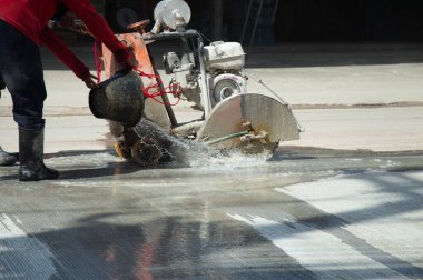 İşçiler beton bir yol kesici kullanıyorlar..