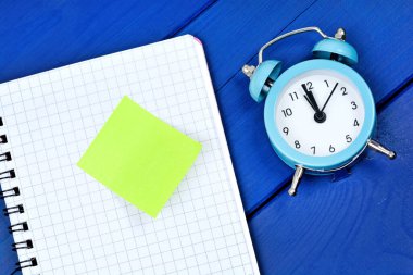 Close up of alarm clock on desk with empty notepad