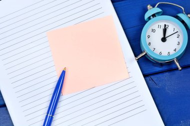 Close up of empty note on a notepad page with pen and alarm clock