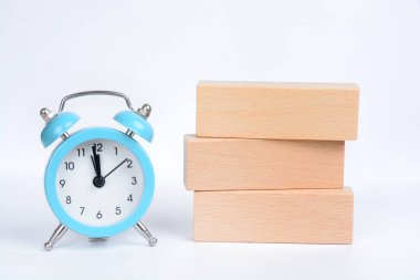 Beyaz arkaplanda alarm saati olan boş tahta bloklar