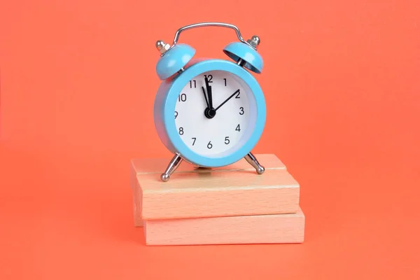 オレンジ色の背景に目覚まし時計が付いている空の木製ブロック — ストック写真