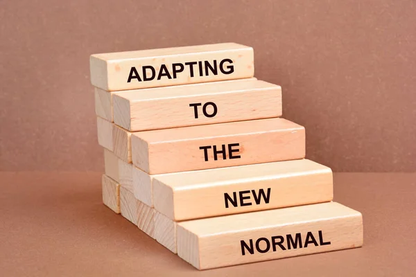 stock image Adapting to the new normal symbol. Wooden blocks with words Adapting to the new normal on brown background