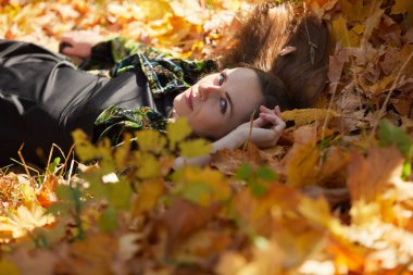 Sonbahar parkında yaprakları dökülmüş genç bir kız.