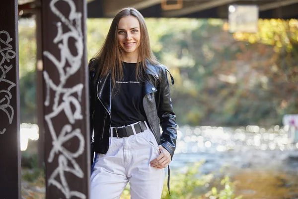 Siyah deri ceketli gülümseyen genç kadın.