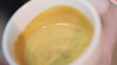 Close up view of pouring milk in cup with coffee 