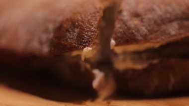 Closeup of persons hand cutting freshly baked sandwich with knife 